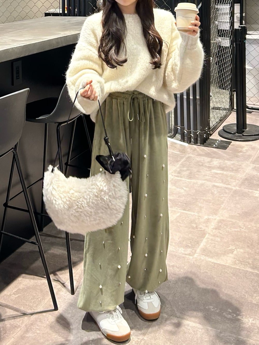 グリーン系のその他パンツ、ホワイト系のニット/セーター、ホワイト系のショルダーバッグを着用したレディースの冬コーディネートの2枚目の写真