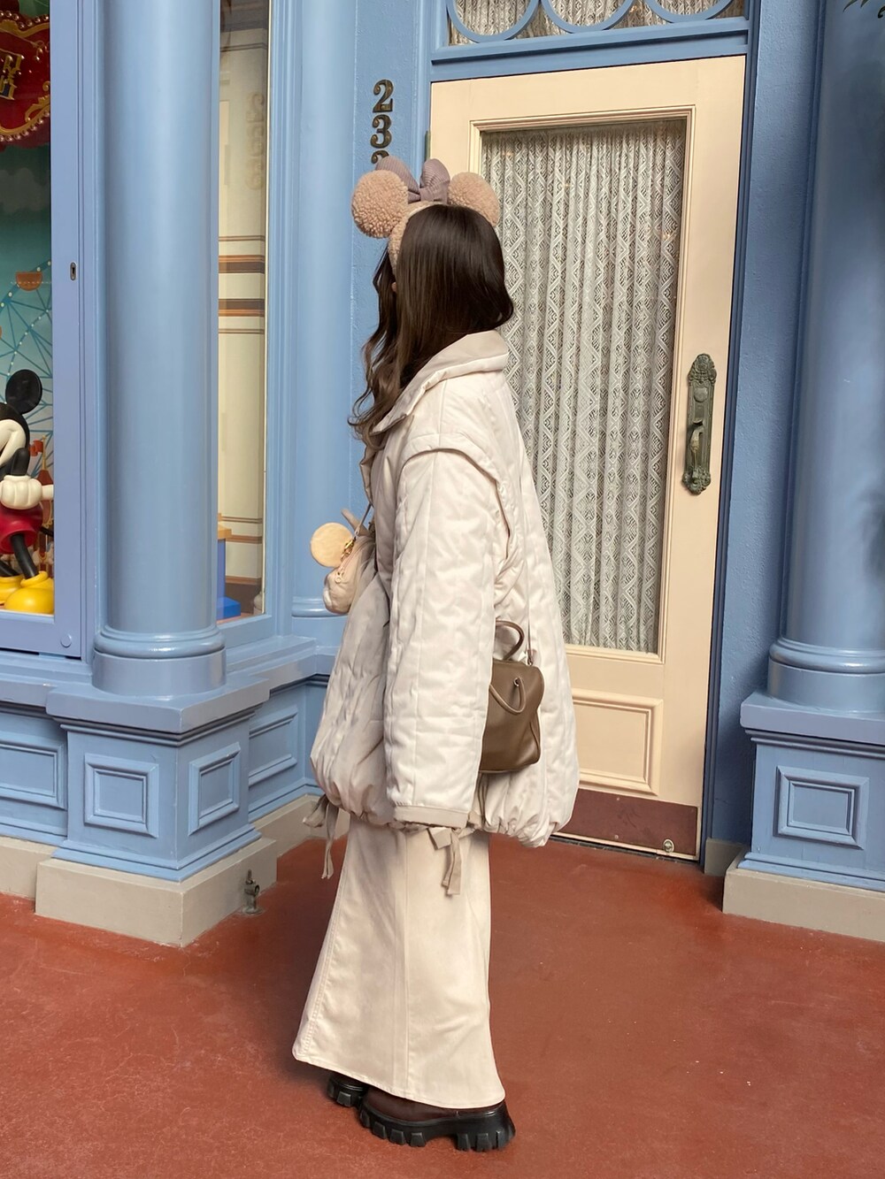 ベージュ系のショルダーバッグ、ホワイト系のダウンジャケット/コート、ホワイト系のニット/セーターを着用したレディースの冬コーディネートの2枚目の写真