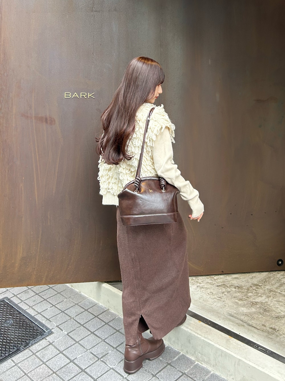 ブラウン系のスカート、ホワイト系のベスト、ホワイト系のニット/セーターを着用したレディースの秋コーディネートの3枚目の写真