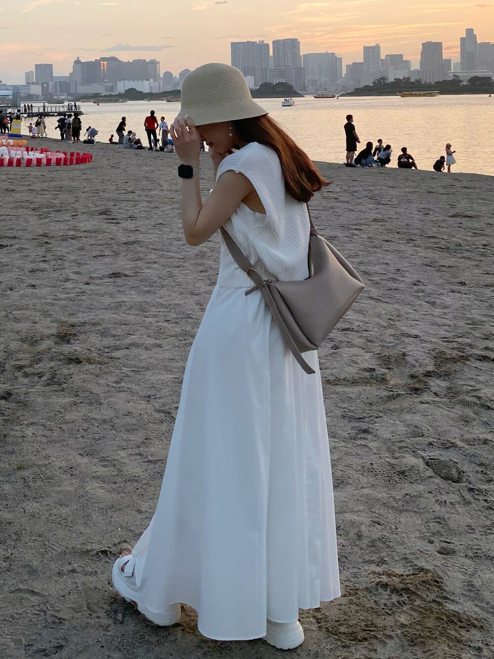 ベージュ系のバッグ、ホワイト系のワンピース、ホワイト系のサンダルを着用したレディースの夏コーディネートの4枚目の写真