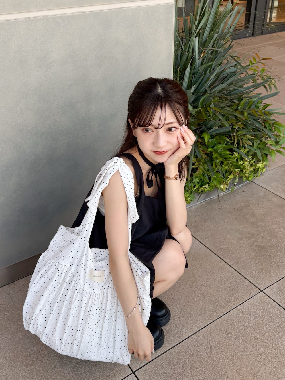 ブラック系のワンピース、ブラック系のブーツ、ホワイト系のカーディガン/ボレロを着用したレディースの夏コーディネートの2枚目の写真