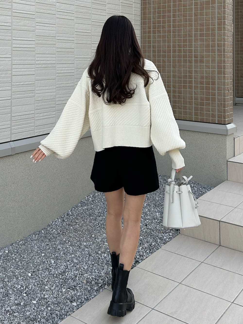 ホワイト系のバッグ、ホワイト系のカーディガン/ボレロ、ブラック系のブーツを着用したレディースの冬コーディネートの3枚目の写真