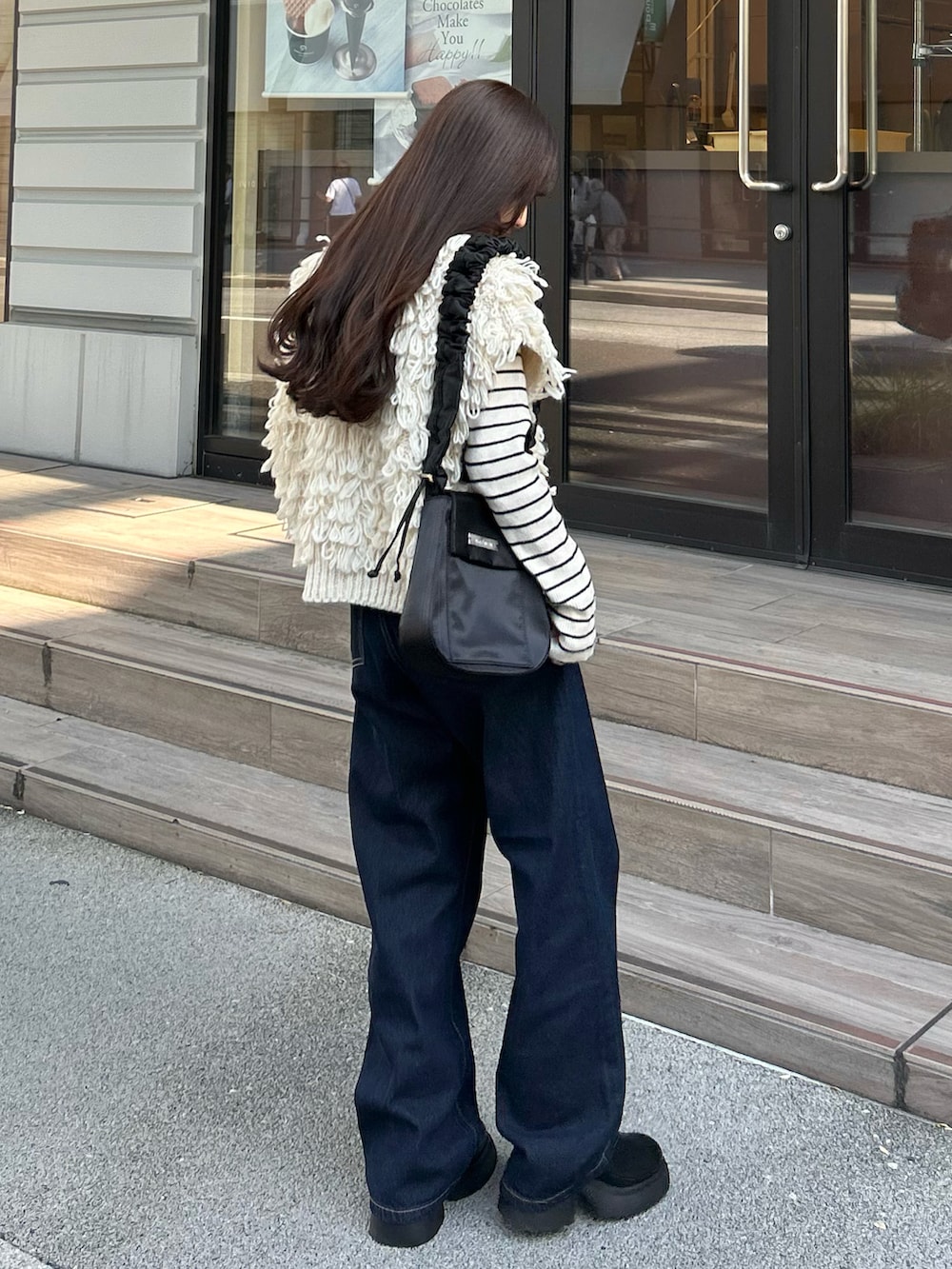 ブルー系のデニムパンツ、ホワイト系のベスト、ホワイト系のニット/セーターを着用したレディースの秋コーディネートの4枚目の写真