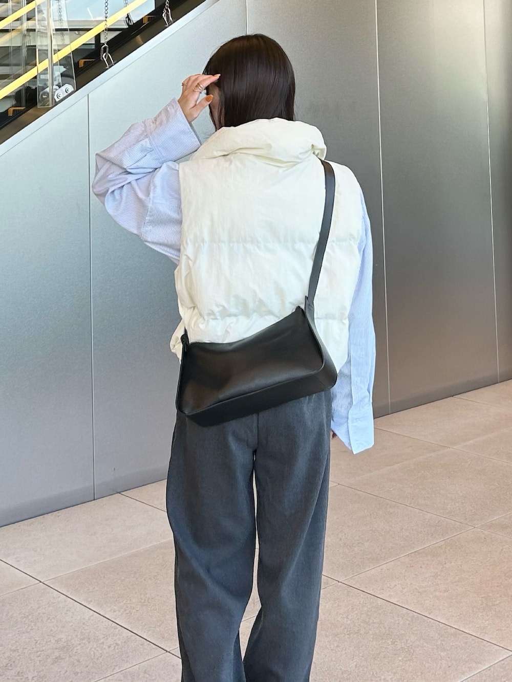 グレー系のスラックス、ホワイト系のダウンベスト、ブルー系のワンピースを着用したレディースの秋コーディネートの4枚目の写真