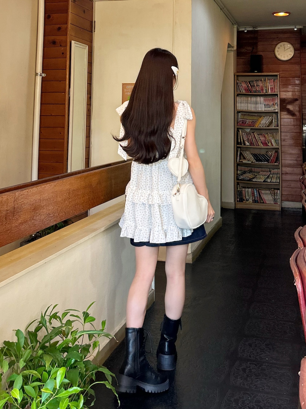 ブルー系のデニムスカート、ホワイト系のハンドバッグ、ブラック系のブーツを着用したレディースの秋コーディネートの4枚目の写真