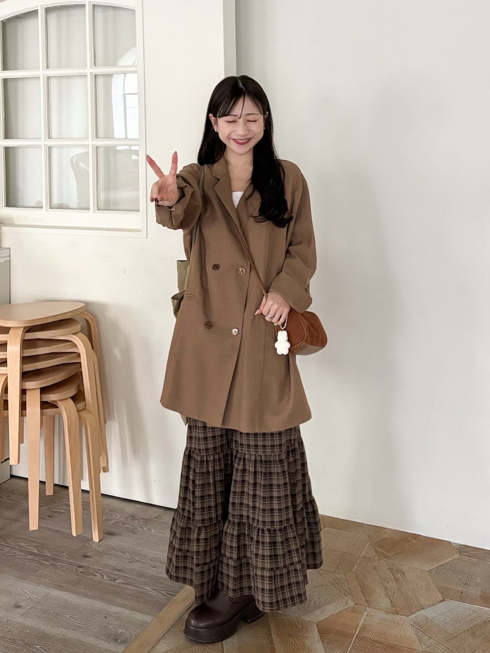 イエロー系のショルダーバッグ、ブラウン系のテーラードジャケット、ブラウン系のブーツを着用したレディースの秋コーディネートの4枚目の写真