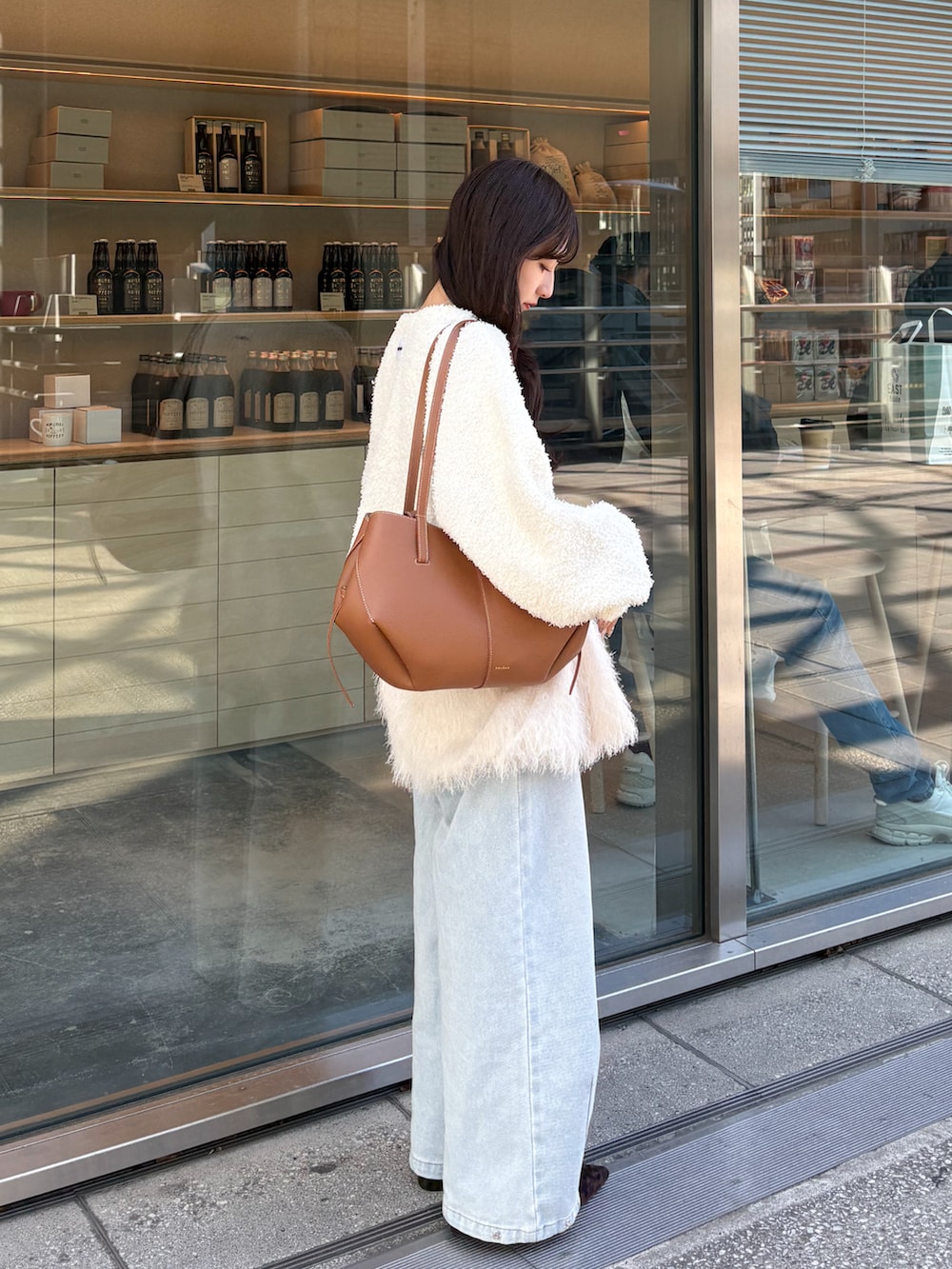 ホワイト系のキャミソール、ホワイト系のカーディガン/ボレロ、ブルー系のデニムパンツを着用したレディースの春コーディネートの3枚目の写真