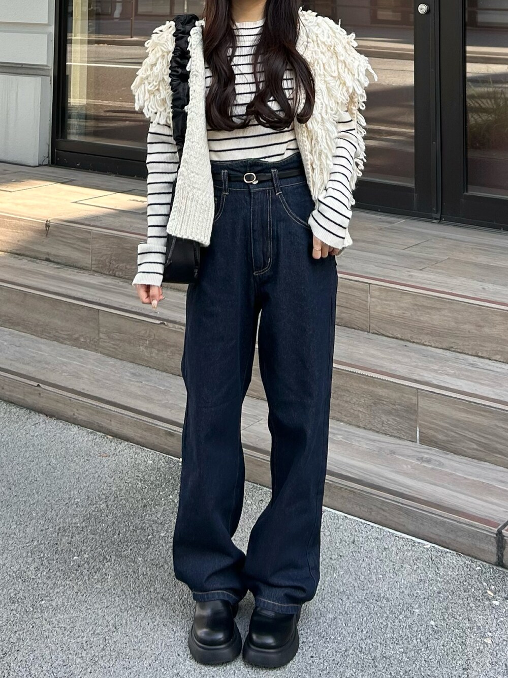 ブルー系のデニムパンツ、ホワイト系のベスト、ホワイト系のニット/セーターを着用したレディースの秋コーディネートの3枚目の写真