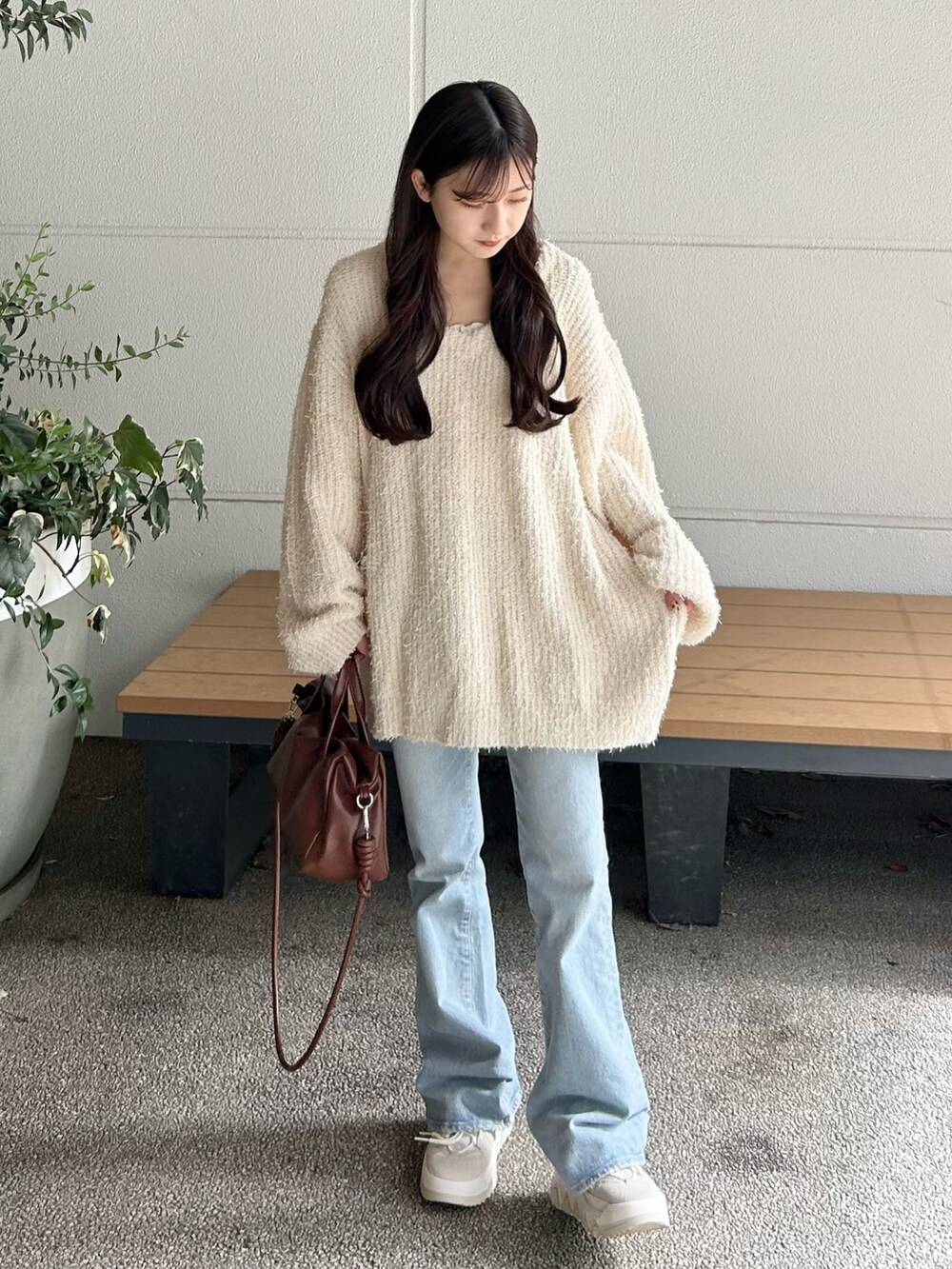 ブルー系のデニムパンツ、ブラウン系のボストンバッグ、ホワイト系のニット/セーターを着用したレディースの秋コーディネートの3枚目の写真