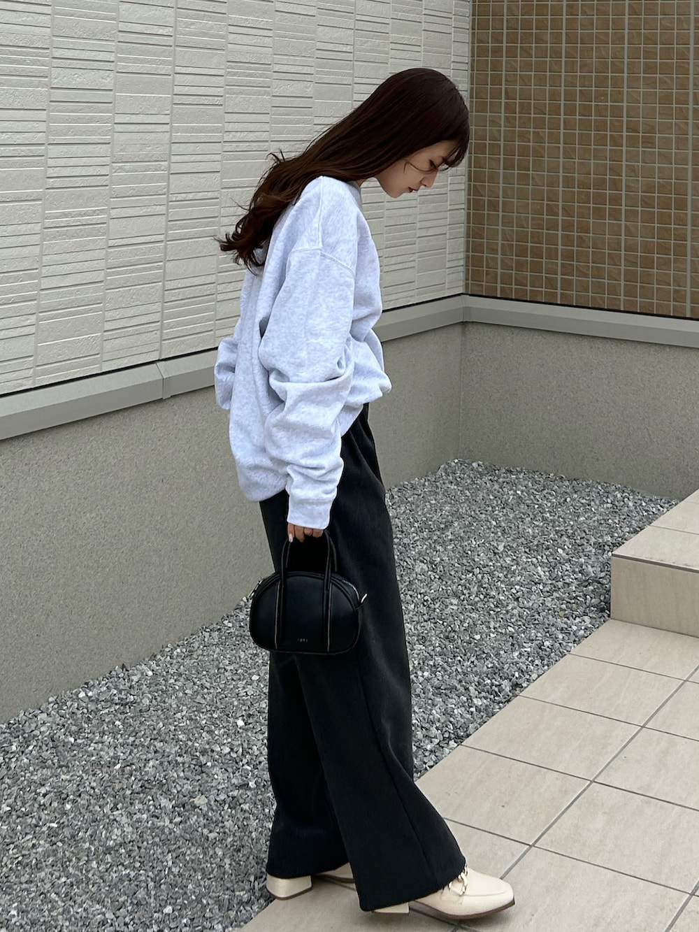 グレー系のスラックス、グレー系のスウェット、ブラック系のバッグを着用したレディースの春コーディネートの2枚目の写真