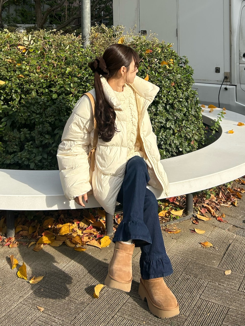 ブルー系のデニムパンツ、ホワイト系のダウンジャケット/コート、ベージュ系のショルダーバッグを着用したレディースの冬コーディネートの3枚目の写真