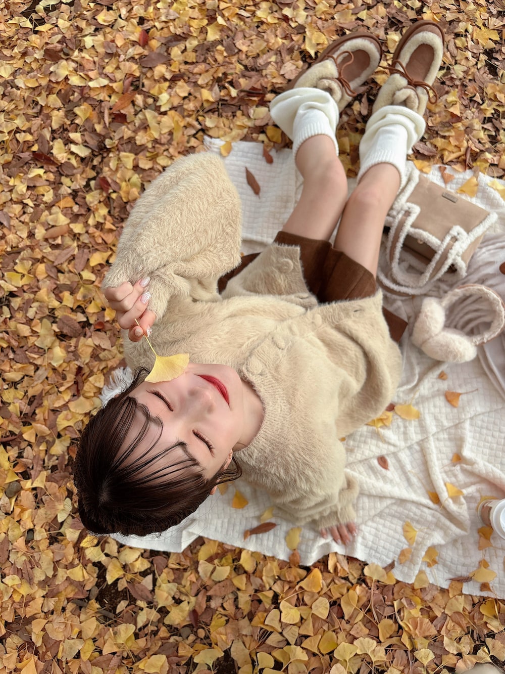 ベージュ系のブーツ、ベージュ系のカーディガン/ボレロ、ホワイト系のマフラーを着用したレディースの秋コーディネートの4枚目の写真