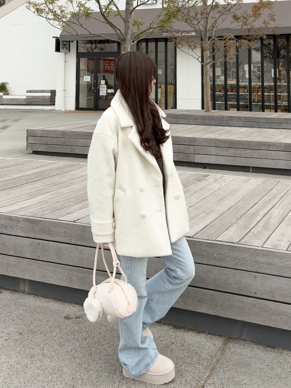 ブラウン系のカーディガン/ボレロ、ブルー系のデニムパンツ、ホワイト系のボストンバッグを着用したレディースの春コーディネートの5枚目の写真