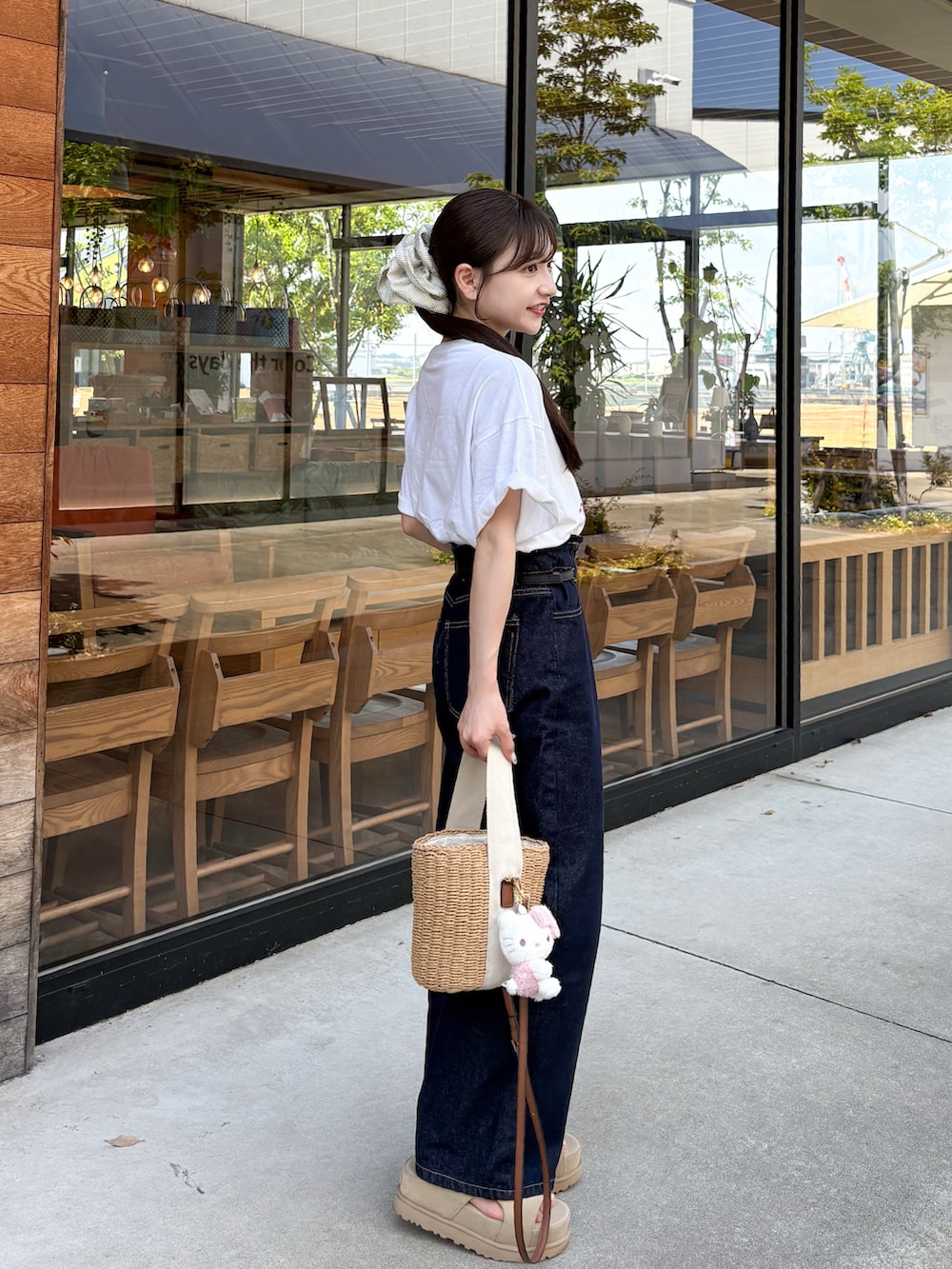 ブルー系のデニムパンツ、ホワイト系のTシャツ/カットソー、ベージュ系のサンダルを着用したレディースの夏コーディネートの2枚目の写真