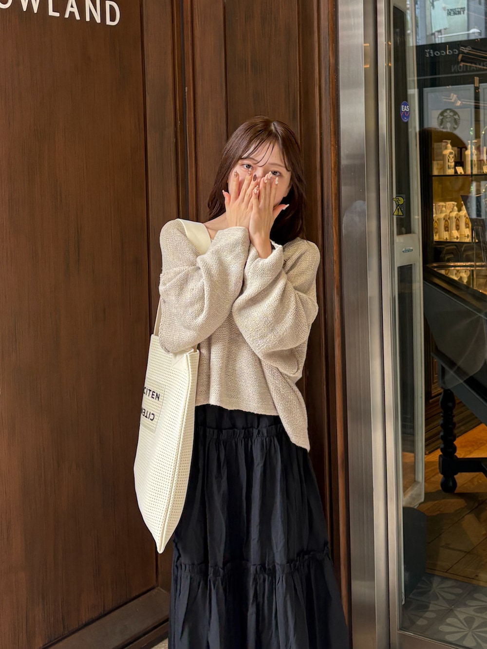 ブラック系のスカート、ベージュ系のニット/セーター、ホワイト系のトートバッグを着用したレディースの秋コーディネートの5枚目の写真