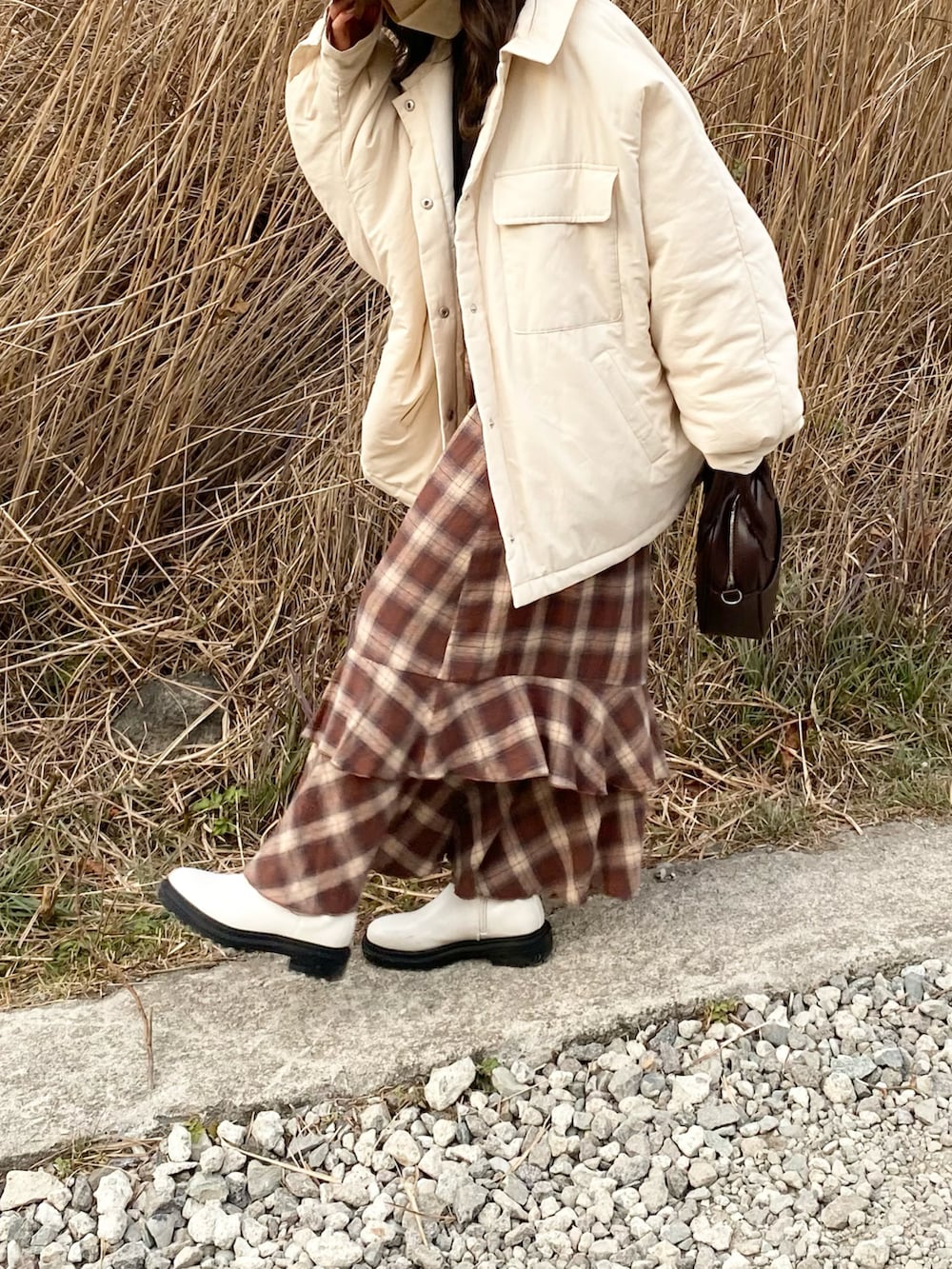 ブラウン系のショルダーバッグ、ブラウン系のスカート、ブラック系のシャツ/ブラウスを着用したレディースの冬コーディネートの4枚目の写真