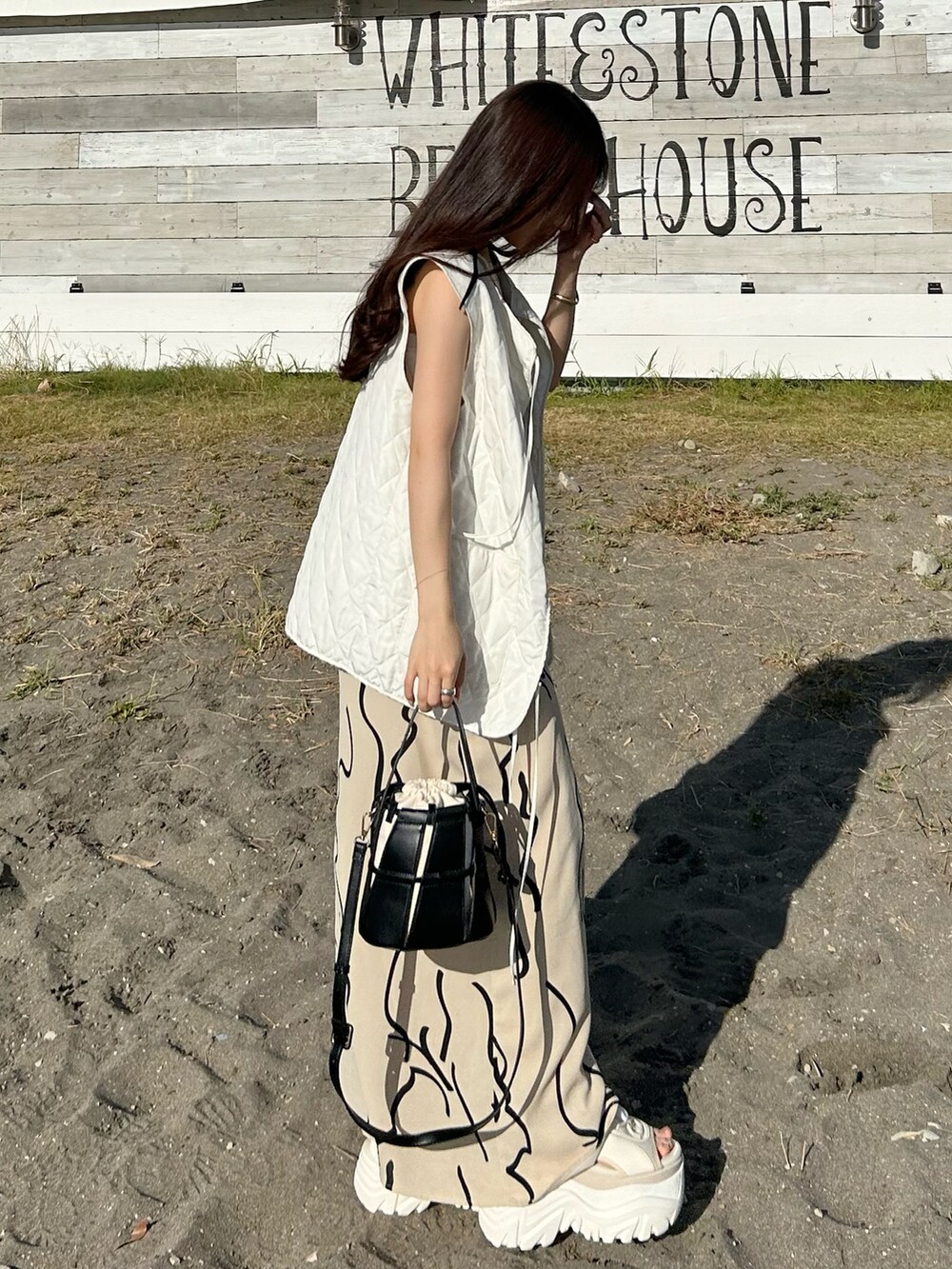 ホワイト系のワンピース、ブラック系のバッグ、ホワイト系のベストを着用したレディースの夏コーディネートの3枚目の写真