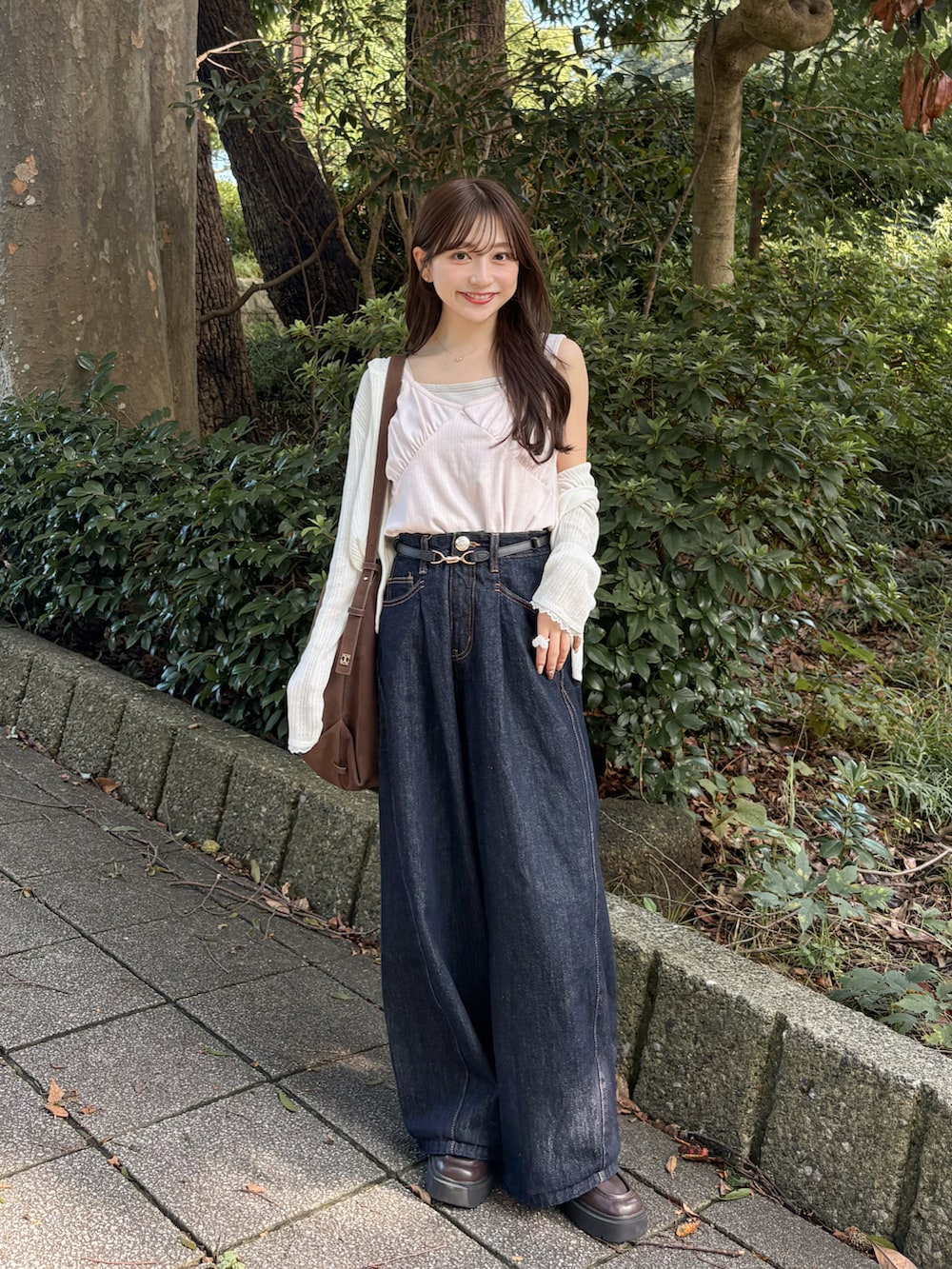 ピンク系のタンクトップ、ブルー系のデニムパンツ、ブラウン系のトートバッグを着用したレディースの秋コーディネートの4枚目の写真