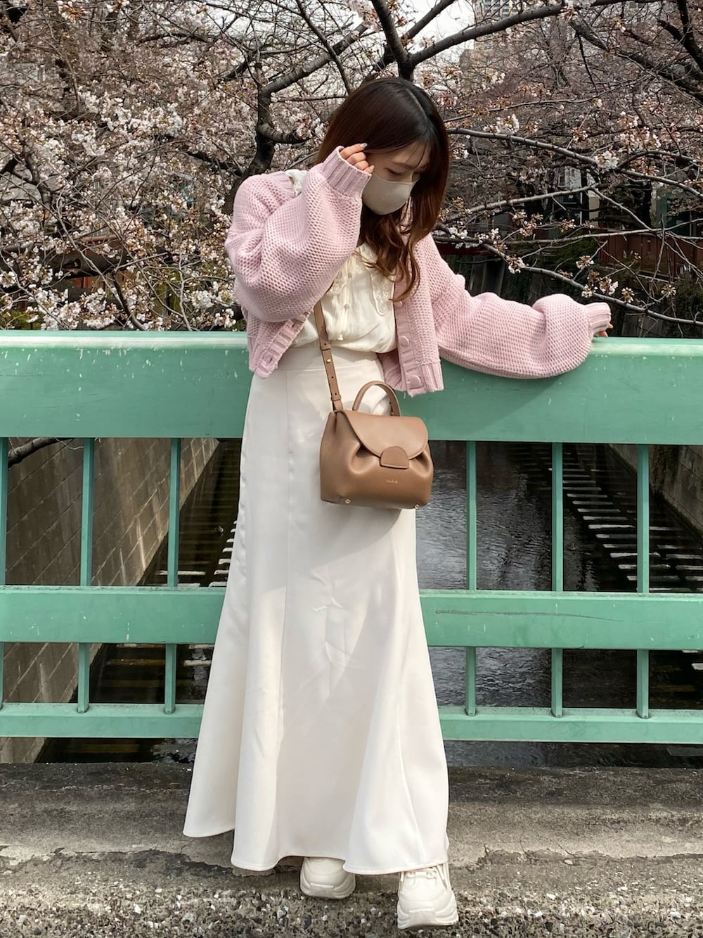 ブラウン系のバッグ、ピンク系のカーディガン/ボレロ、ホワイト系のスカートを着用したレディースの春コーディネートの2枚目の写真
