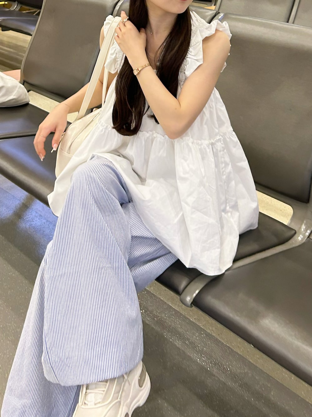 ホワイト系のトップス、ホワイト系のバッグ、ブルー系のパンツを着用したレディースの夏コーディネートの2枚目の写真