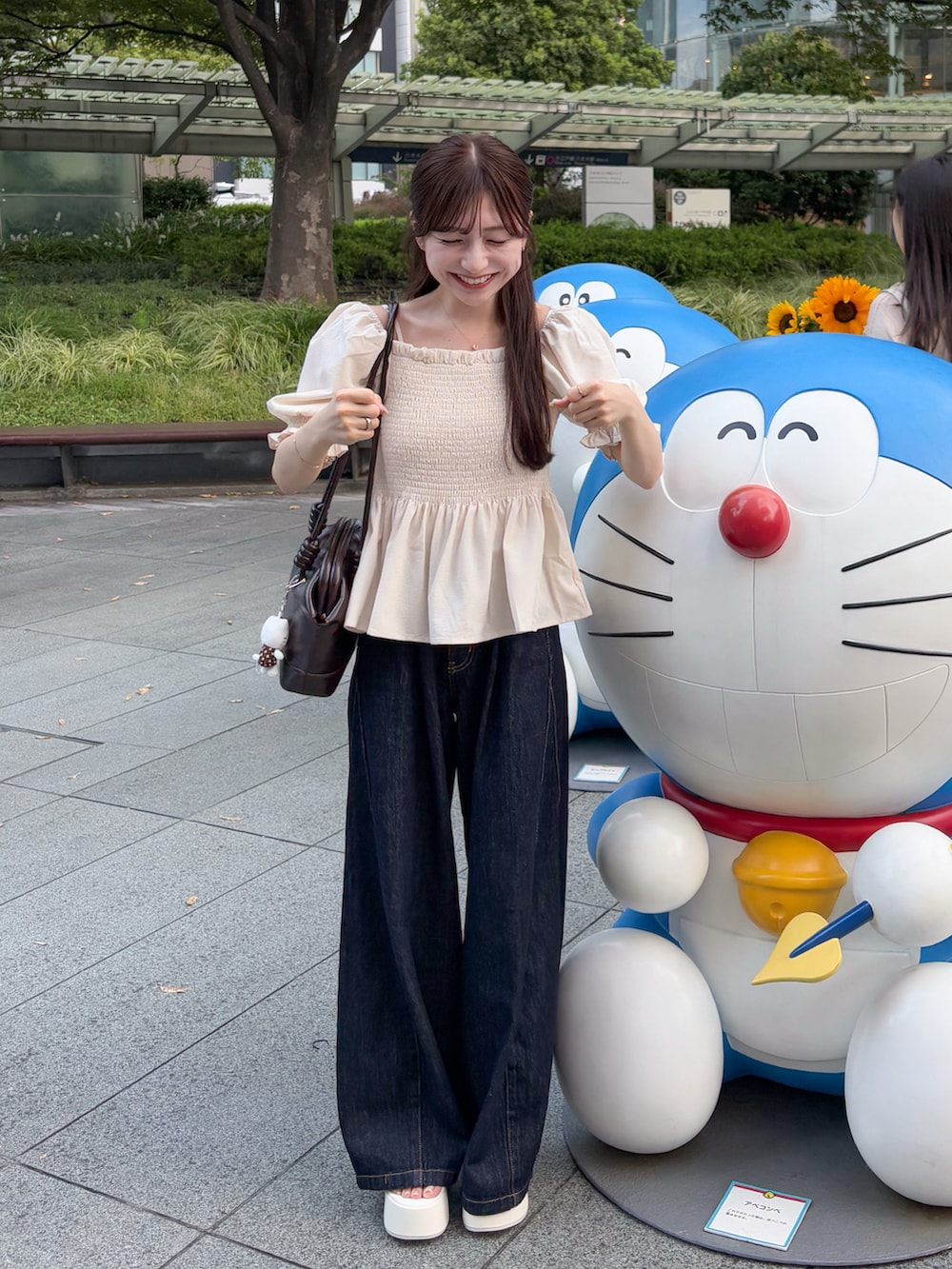 ブルー系のデニムパンツ、ホワイト系のトップス、ブラウン系のショルダーバッグを着用したレディースの夏コーディネートの2枚目の写真
