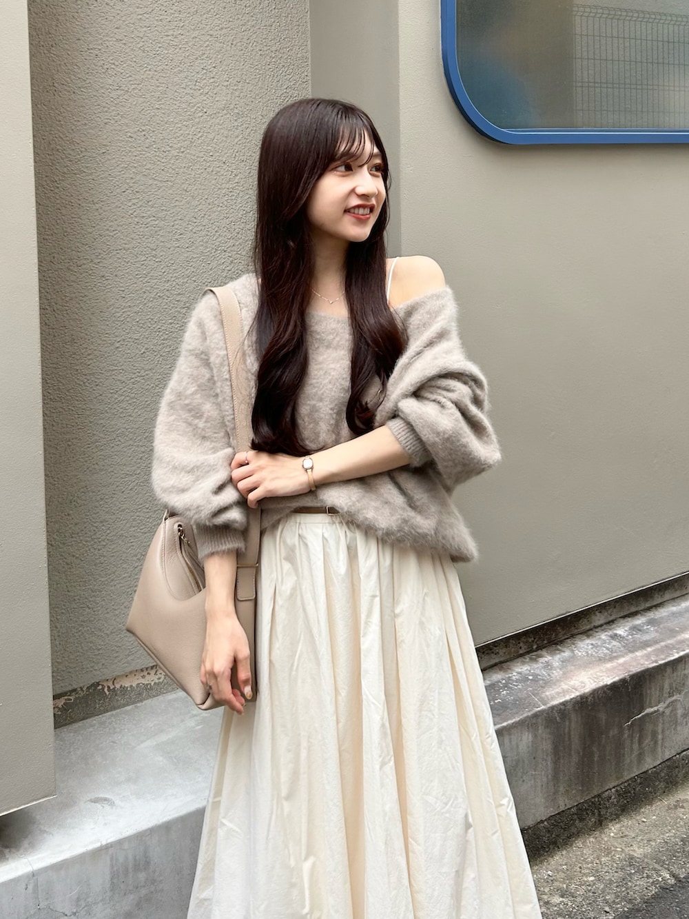 ベージュ系のバッグ、ブラウン系のニット/セーター、ホワイト系のスカートを着用したレディースの秋コーディネートの2枚目の写真