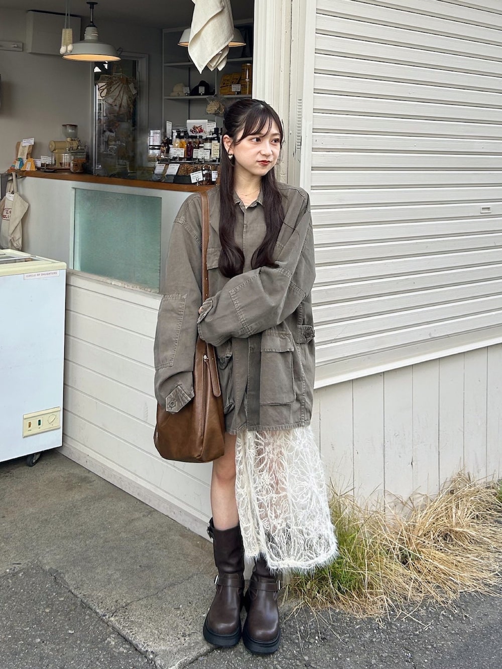 ブラウン系のデニムジャケット、ブラウン系のショルダーバッグ、ブラウン系のブーツを着用したレディースの秋コーディネートの4枚目の写真