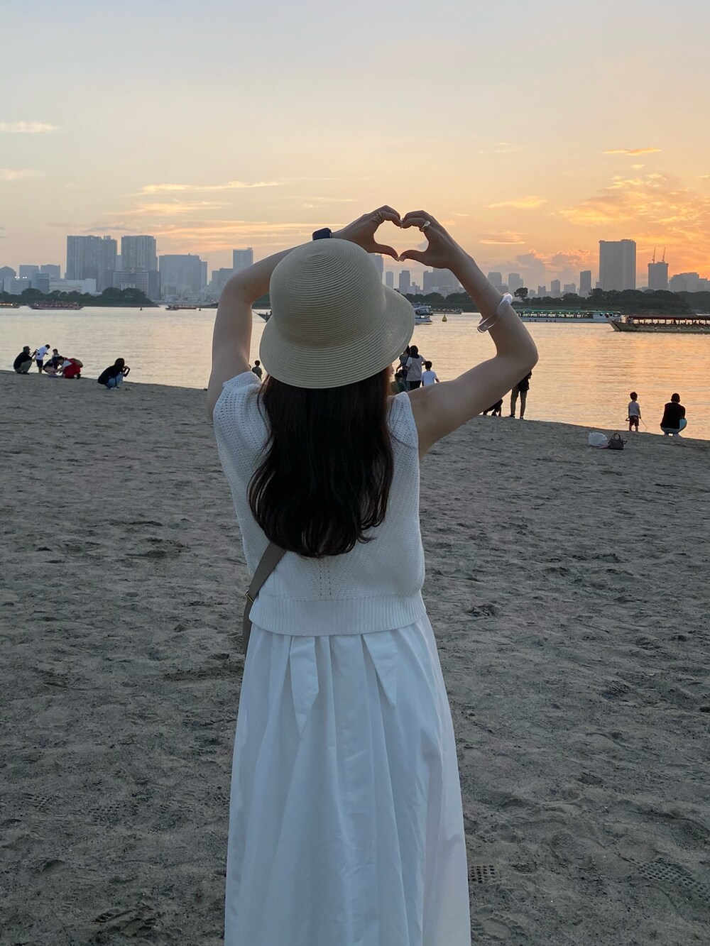 ベージュ系のバッグ、ホワイト系のワンピース、ホワイト系のサンダルを着用したレディースの夏コーディネートの3枚目の写真