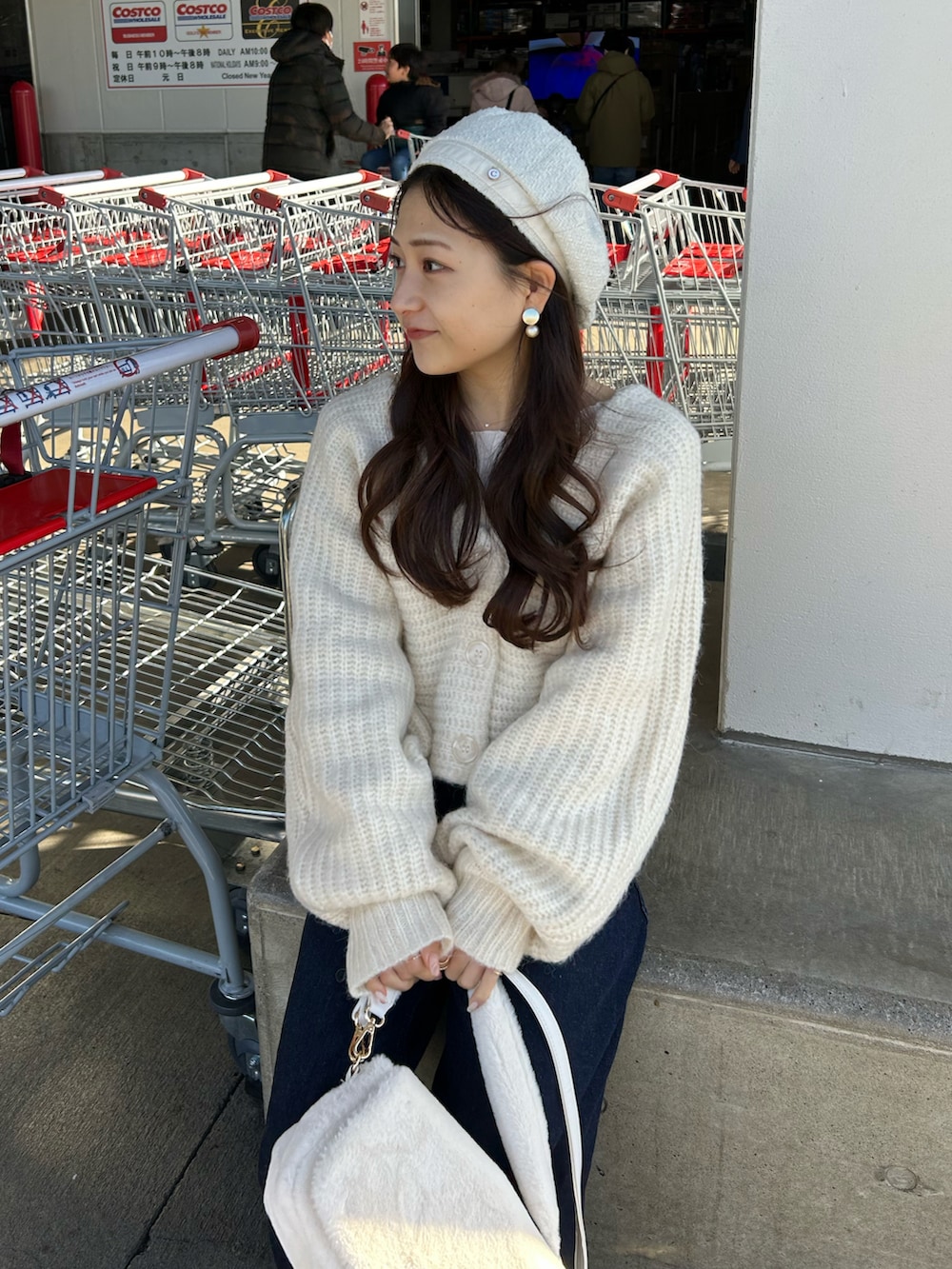 ブルー系のデニムパンツ、ホワイト系のショルダーバッグ、ホワイト系のローファーを着用したレディースの冬コーディネートの3枚目の写真