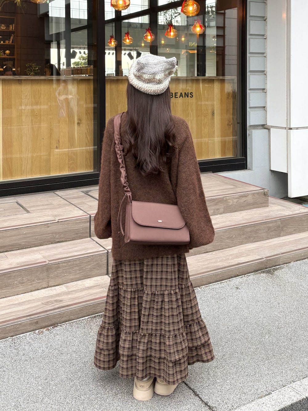 ブラウン系のニット/セーター、ブラウン系のスカート、ホワイト系のその他アウターを着用したレディースの冬コーディネートの4枚目の写真