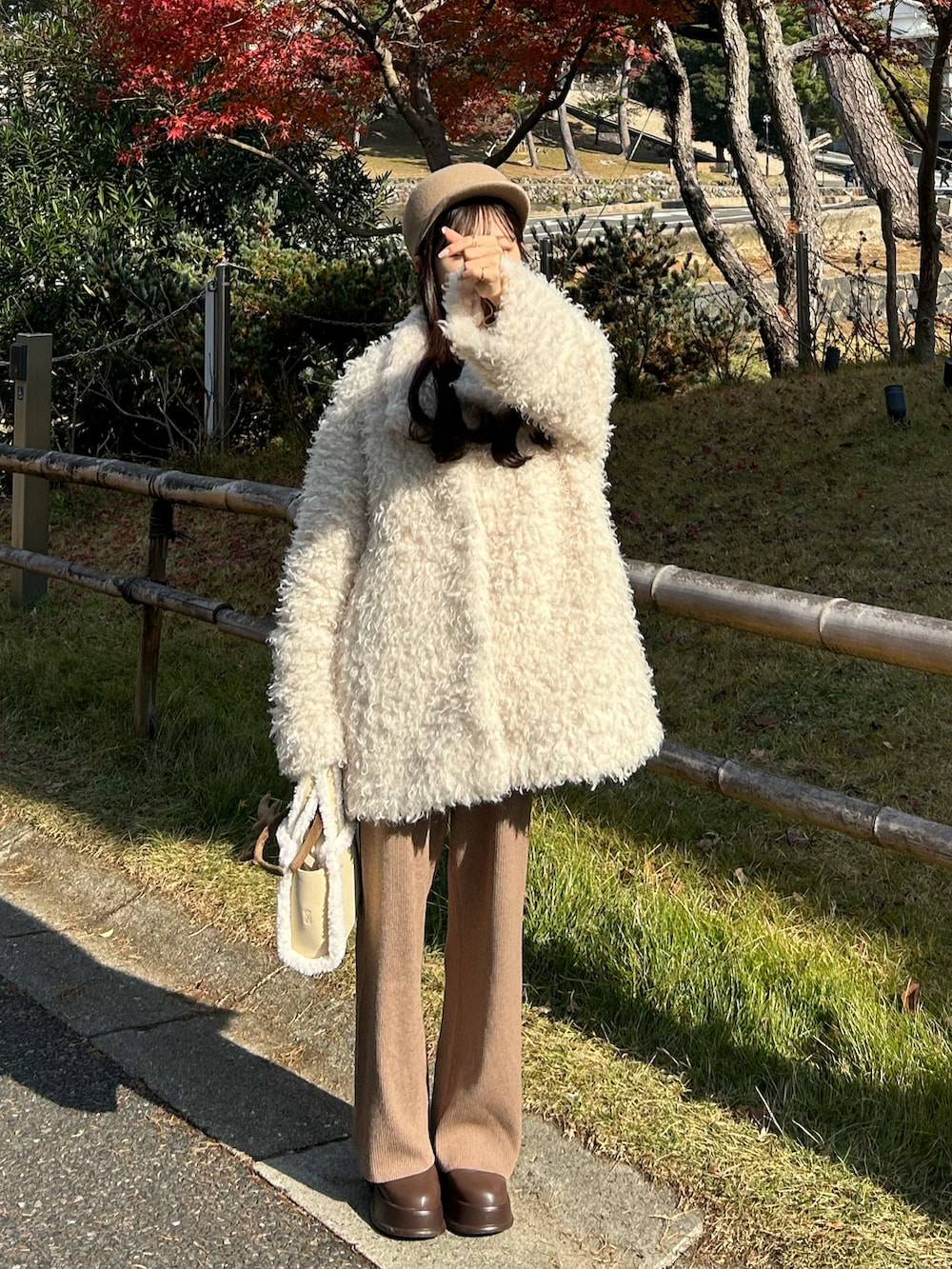 ホワイト系のハンドバッグ、ホワイト系のその他アウター、ブラウン系のブーツを着用したレディースの冬コーディネートの3枚目の写真