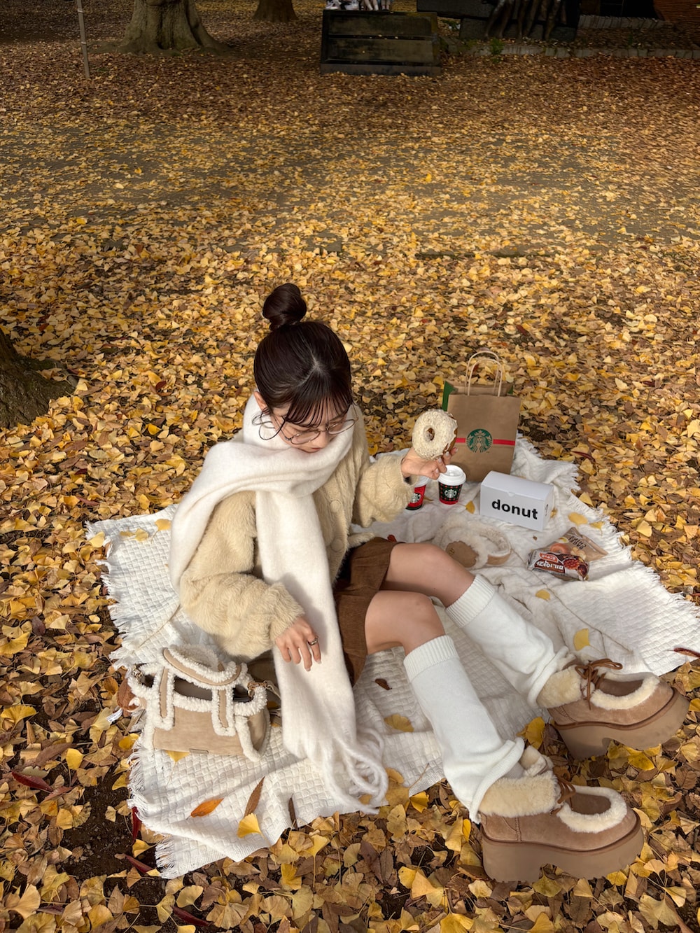 ベージュ系のブーツ、ベージュ系のカーディガン/ボレロ、ホワイト系のマフラーを着用したレディースの秋コーディネートの3枚目の写真