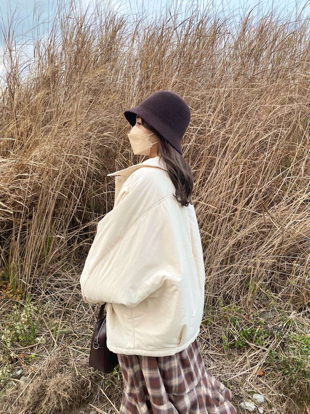 ブラウン系のショルダーバッグ、ブラウン系のスカート、ブラック系のシャツ/ブラウスを着用したレディースの冬コーディネートの3枚目の写真