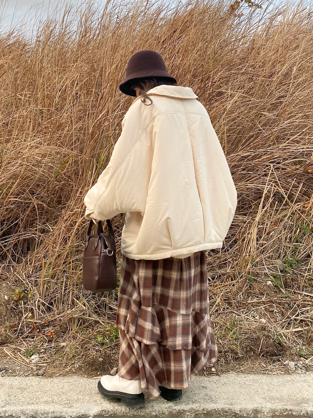 ブラウン系のショルダーバッグ、ブラウン系のスカート、ブラック系のシャツ/ブラウスを着用したレディースの冬コーディネートの2枚目の写真