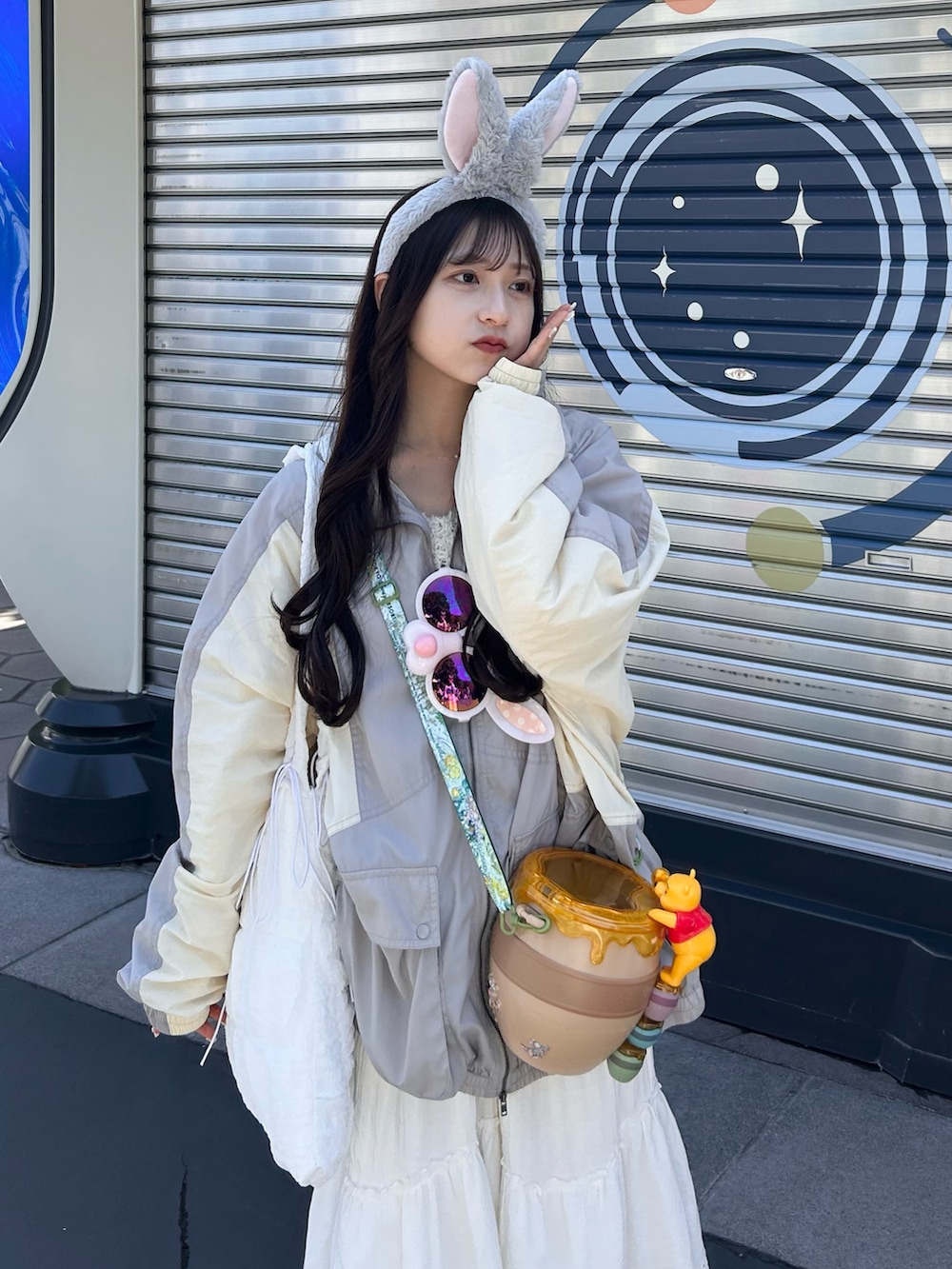 グレー系のナイロンジャケット、ホワイト系のスカート、ホワイト系のトートバッグを着用したレディースの春コーディネートの5枚目の写真