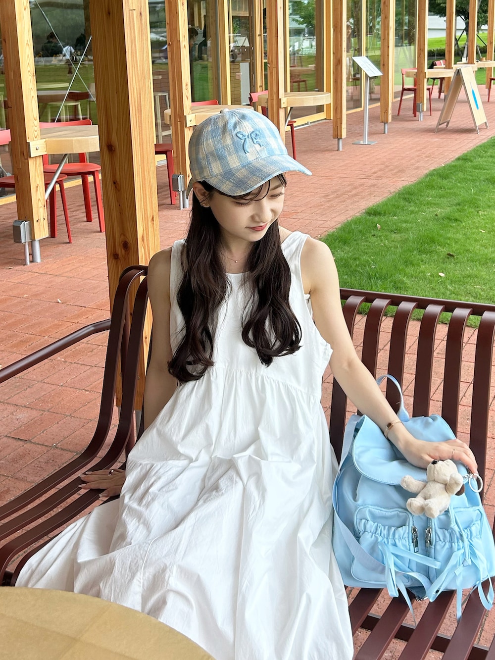 ホワイト系のワンピース、ブルー系のバックパック/リュック、ベージュ系のサンダルを着用したレディースの夏コーディネートの4枚目の写真