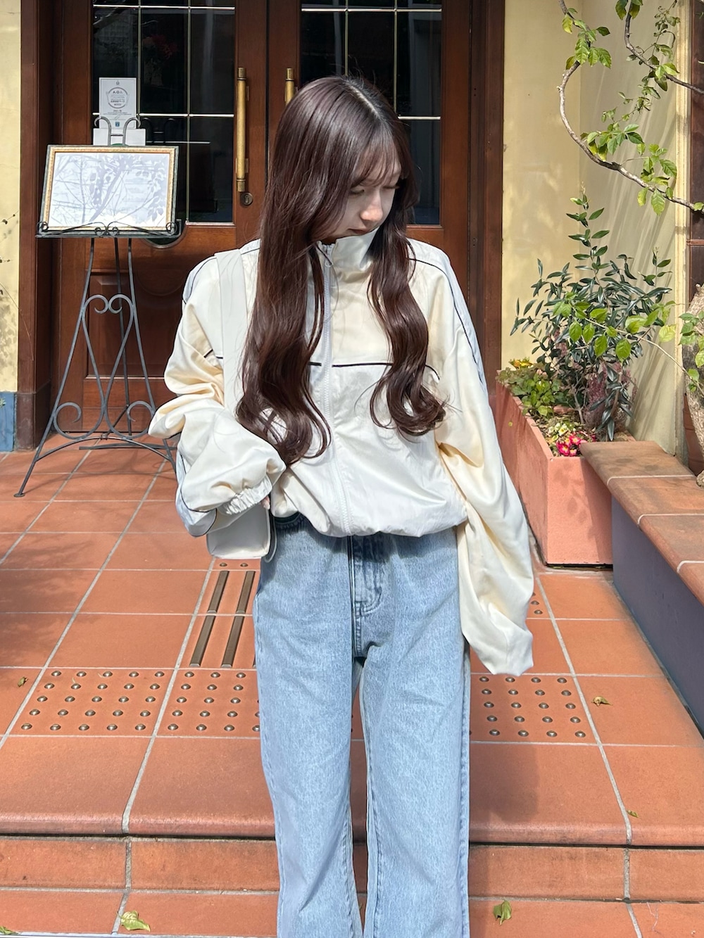 ブルー系のデニムパンツ、ホワイト系のブルゾン、ホワイト系のショルダーバッグを着用したレディースの春コーディネートの3枚目の写真