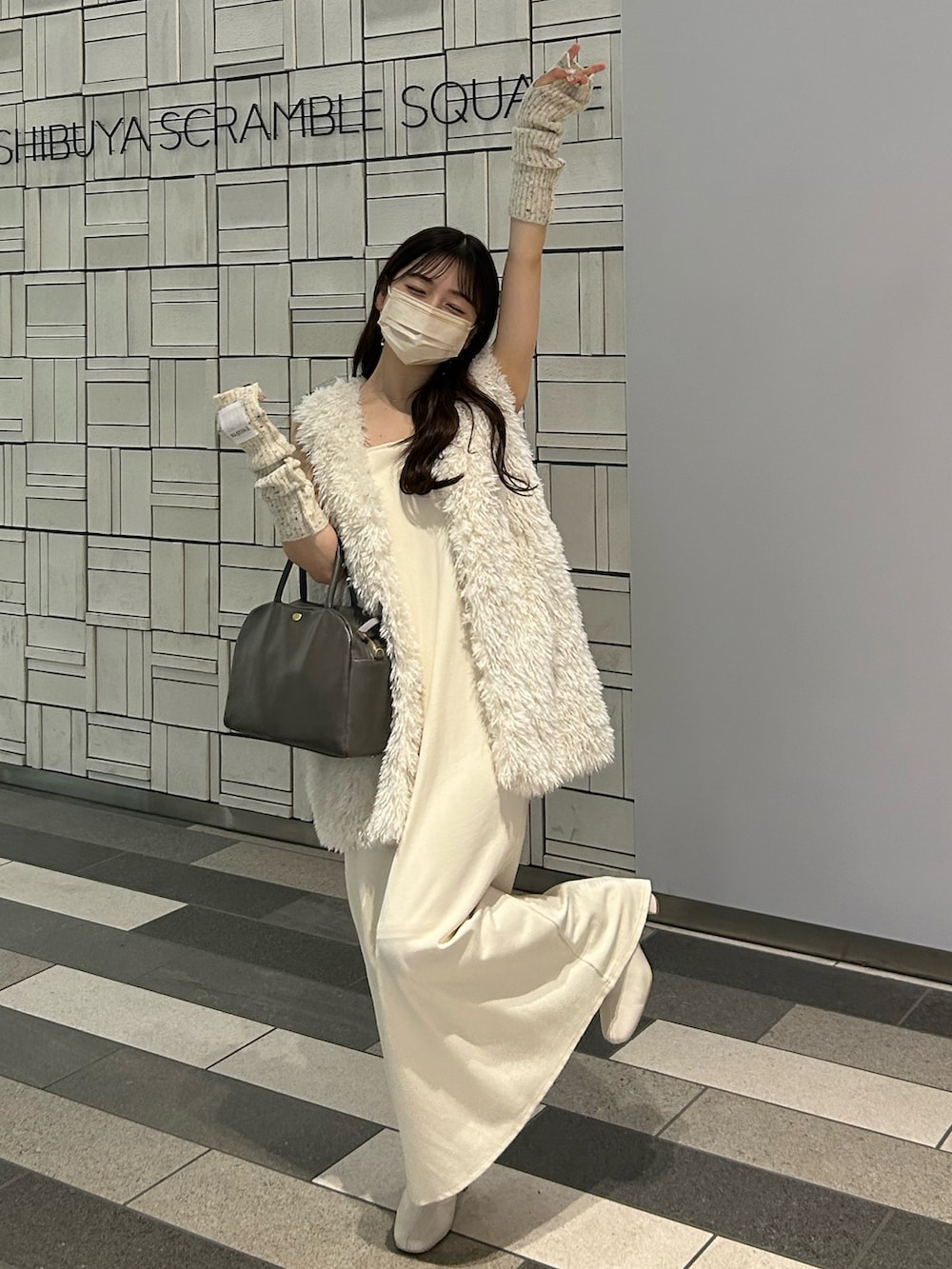 グレー系のショルダーバッグ、ホワイト系のワンピース、ホワイト系のダウンベストを着用したレディースの秋コーディネートの2枚目の写真