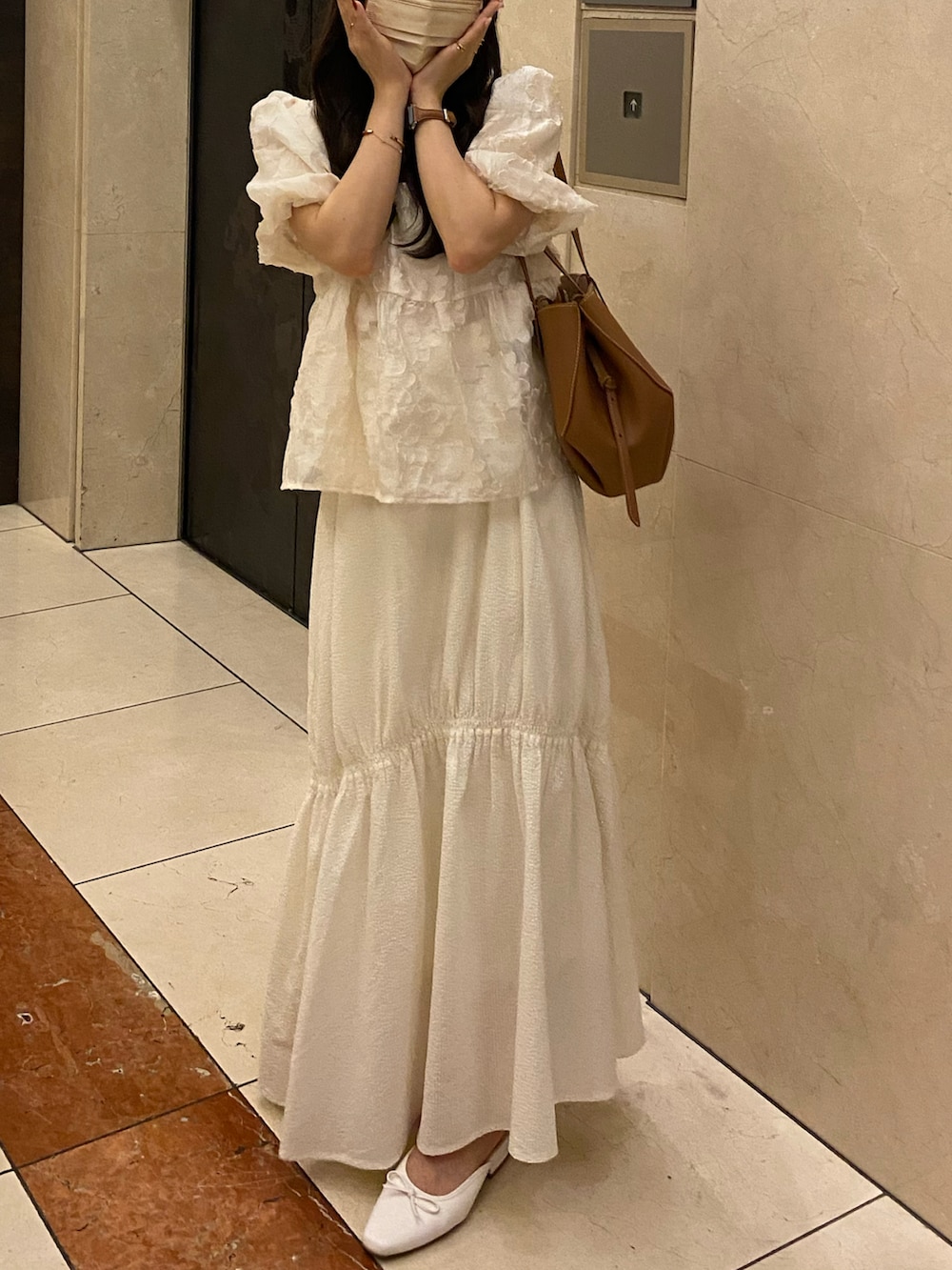 ブラウン系のバッグ、ホワイト系のスカート、ホワイト系のシャツ/ブラウスを着用したレディースの秋コーディネートの2枚目の写真