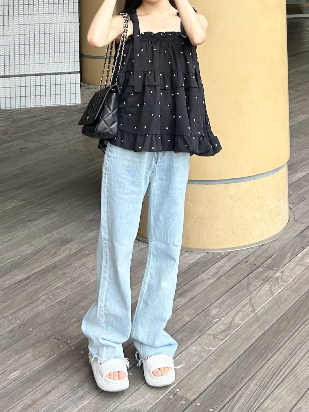 ブルー系のデニムパンツ、ブラック系のトップス、ホワイト系のサンダルを着用したレディースの夏コーディネートの3枚目の写真