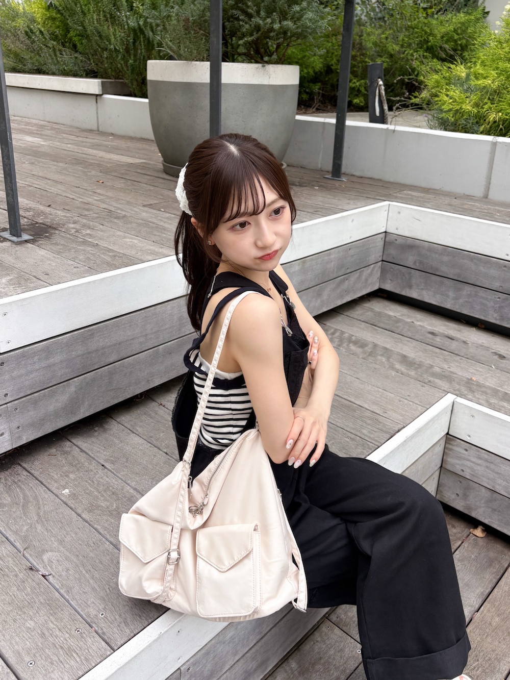 ホワイト系のトートバッグ、ブラック系のデニムパンツ、ホワイト系のサンダルを着用したレディースの夏コーディネートの5枚目の写真