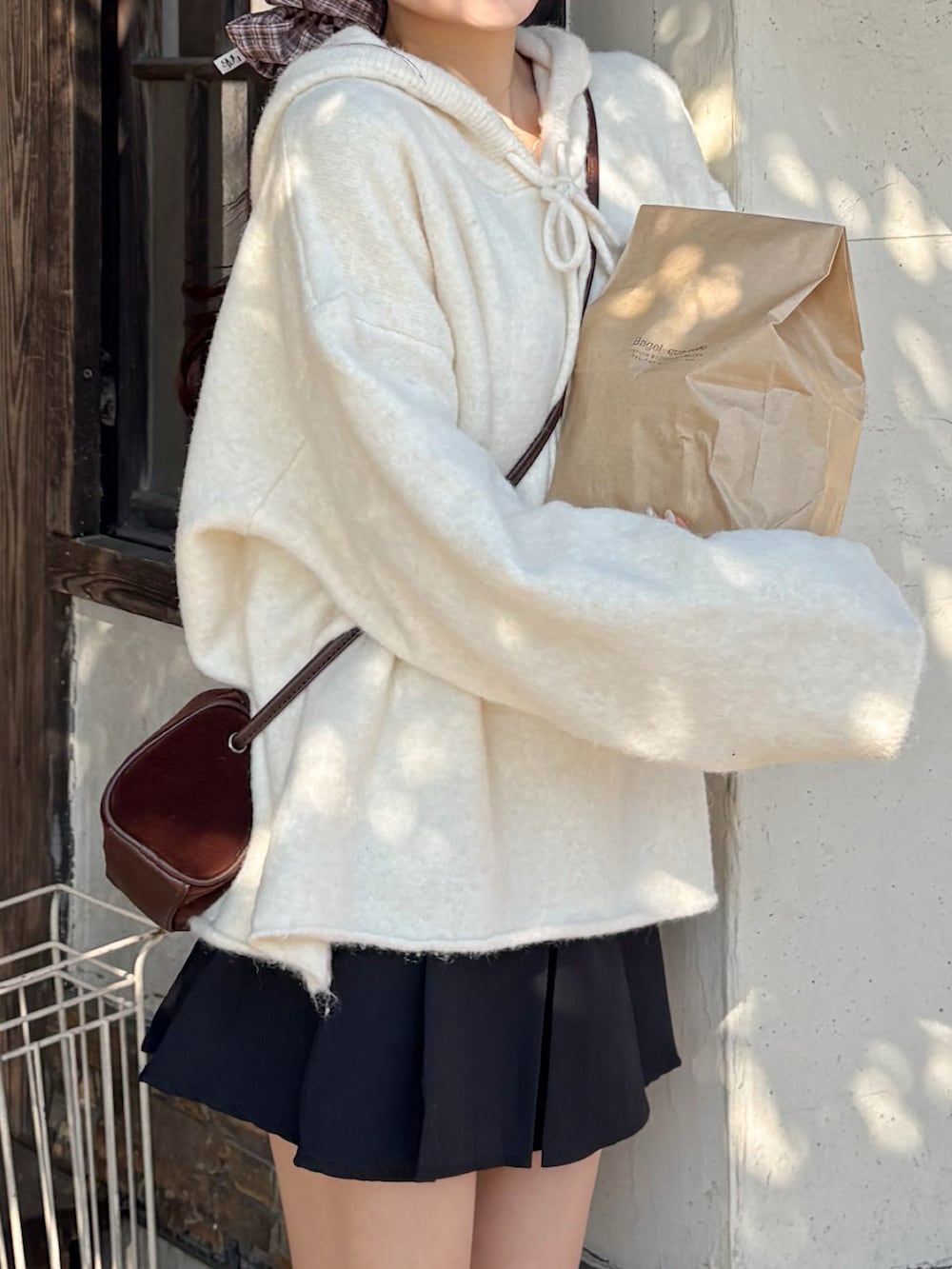 ホワイト系のパーカー、ブラック系のスカート、ブラウン系のローファーを着用したレディースの秋コーディネートの4枚目の写真