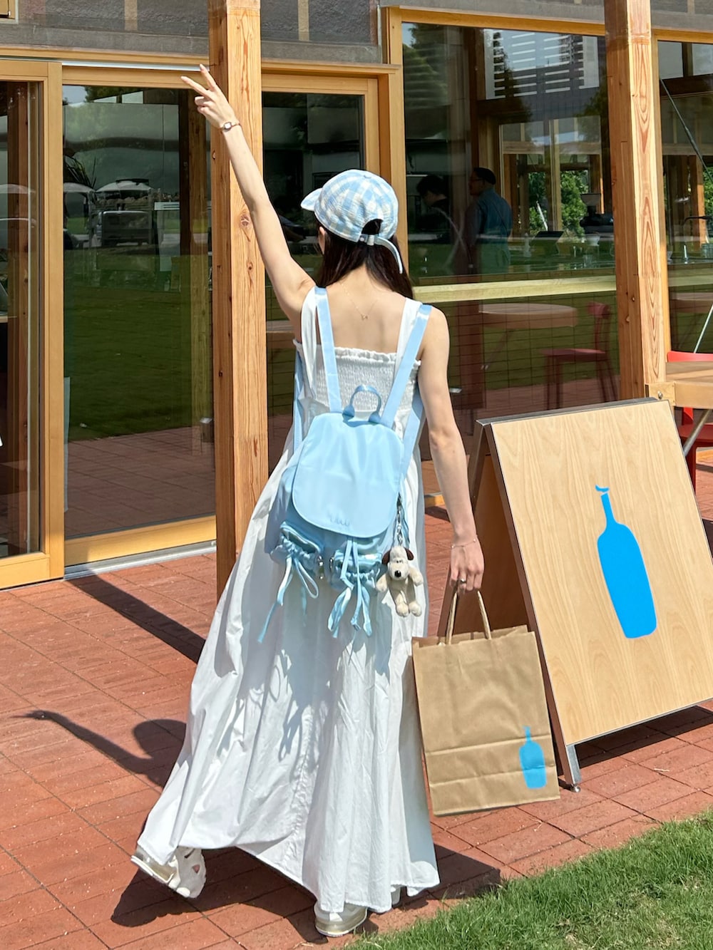 ホワイト系のワンピース、ブルー系のバックパック/リュック、ベージュ系のサンダルを着用したレディースの夏コーディネートの2枚目の写真