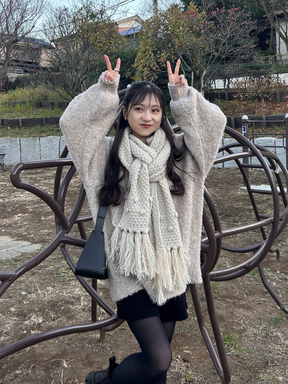 ホワイト系のダッフルコート、ブラック系のショルダーバッグ、ブラック系のブーツを着用したレディースの冬コーディネートの5枚目の写真