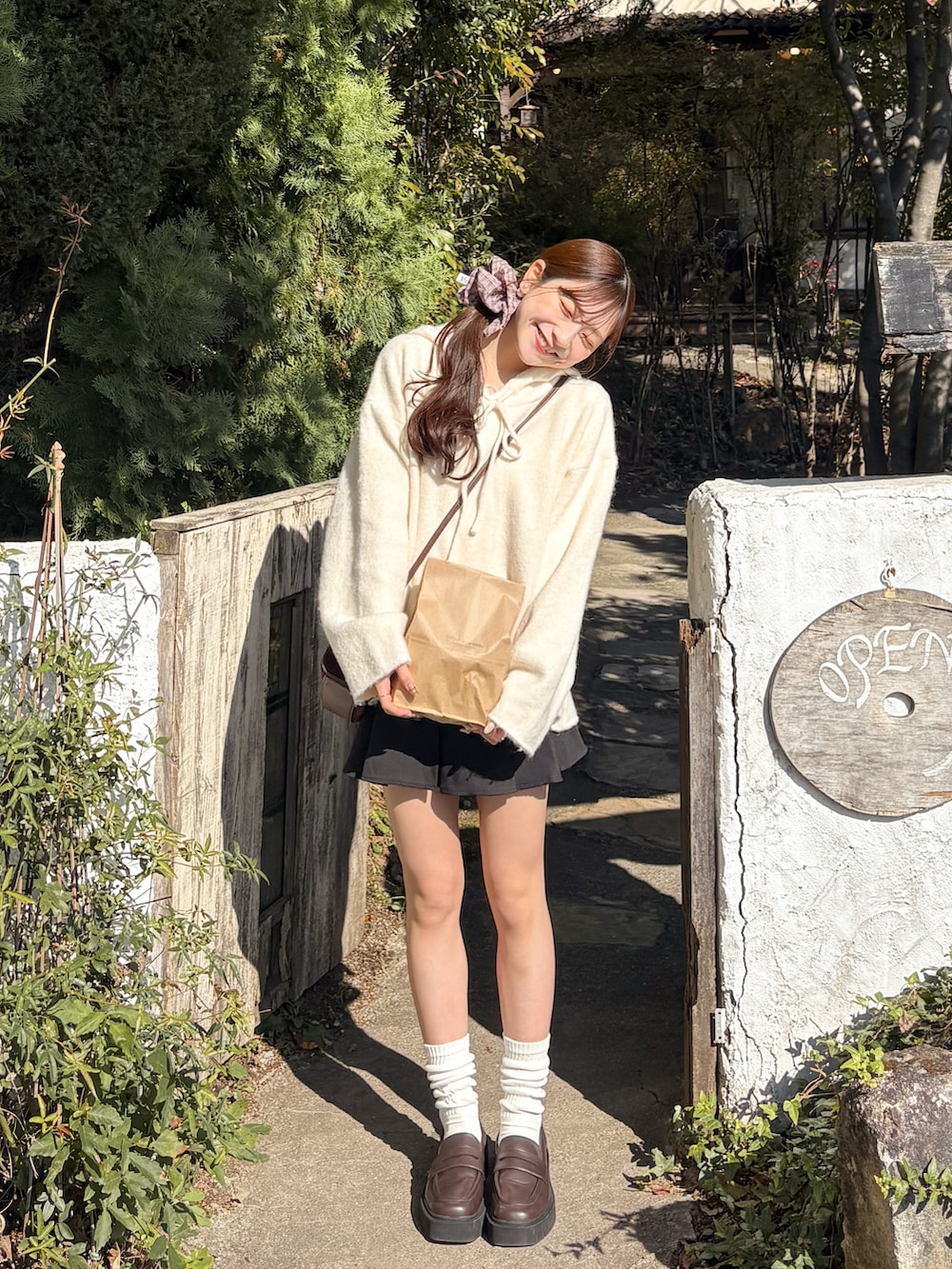 ホワイト系のパーカー、ブラック系のスカート、ブラウン系のローファーを着用したレディースの秋コーディネートの3枚目の写真