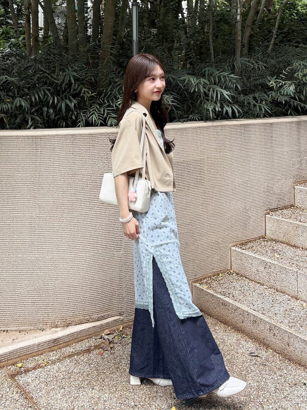 ベージュ系のその他アウター、ホワイト系のワンピース、ブルー系のデニムパンツを着用したレディースの秋コーディネートの2枚目の写真