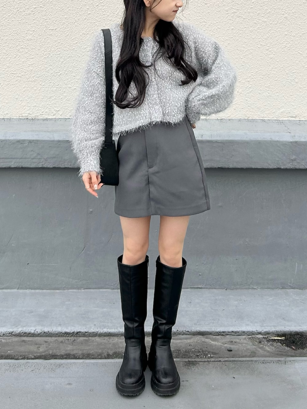 ブラック系のブーツ、グレー系のスカート、グレー系のカーディガン/ボレロを着用したレディースの冬コーディネートの2枚目の写真