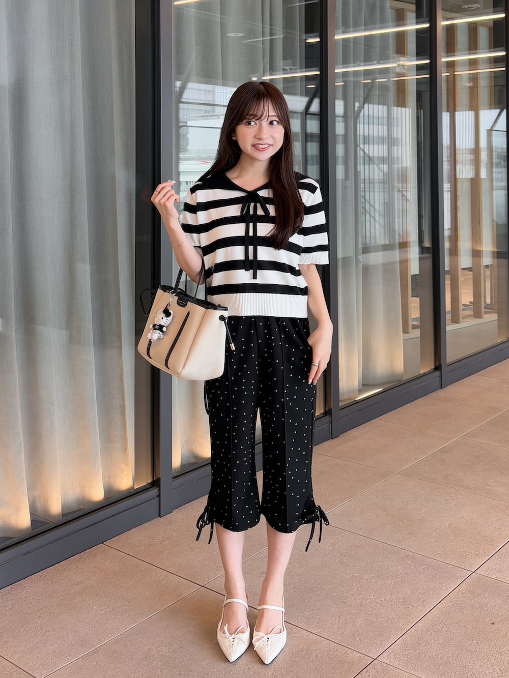 ブラック系のパンツ、グレー系のニット/セーター、ホワイト系のトートバッグを着用したレディースの夏コーディネートの3枚目の写真