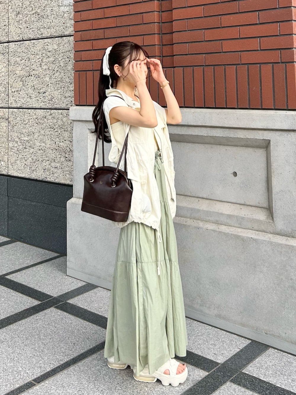 ブラウン系のショルダーバッグ、ホワイト系のミリタリージャケット、ホワイト系のキャミソールを着用したレディースの秋コーディネートの2枚目の写真