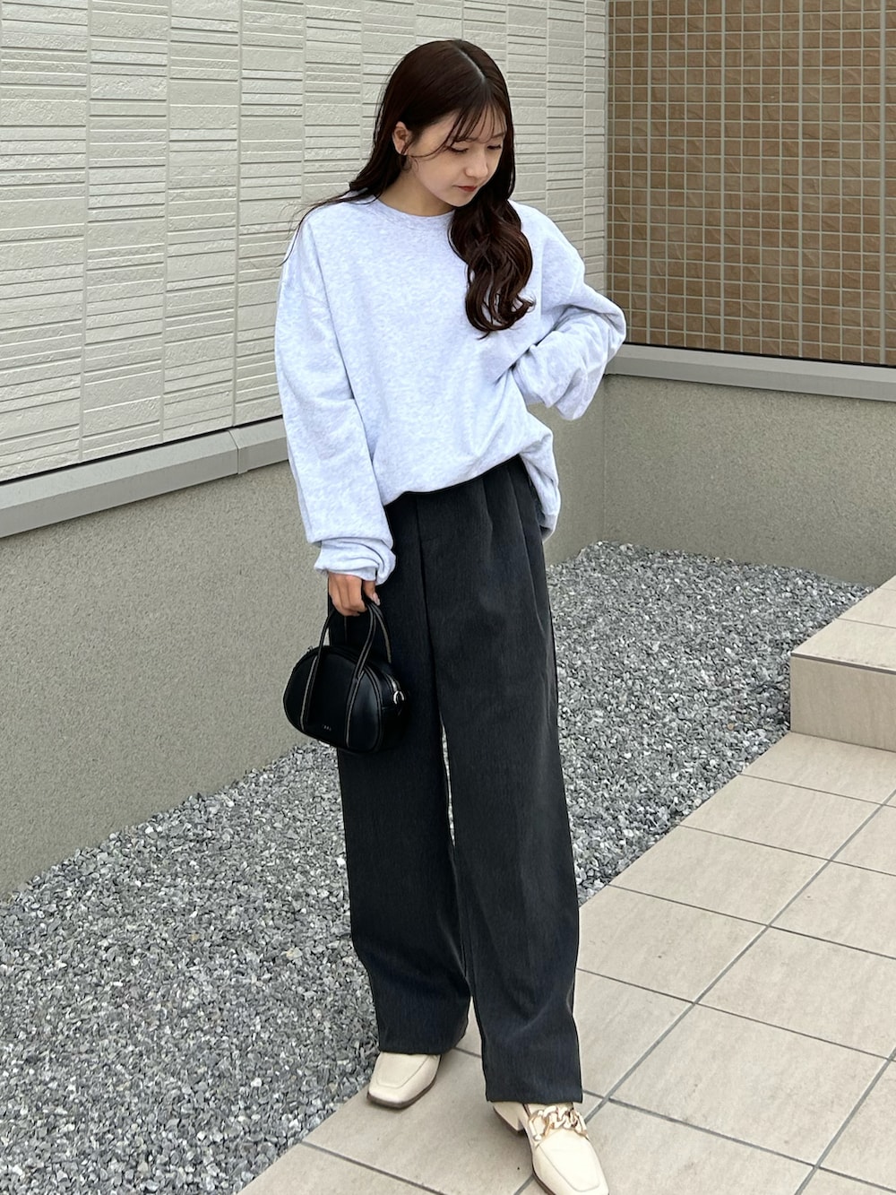 グレー系のスラックス、グレー系のスウェット、ブラック系のバッグを着用したレディースの春コーディネートの3枚目の写真